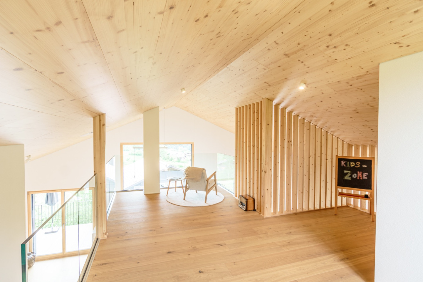 Galerie unter der Dachschräge mit Sitzecke, Raumtrenner aus Holzlamellen und Spielbereich für Kinder