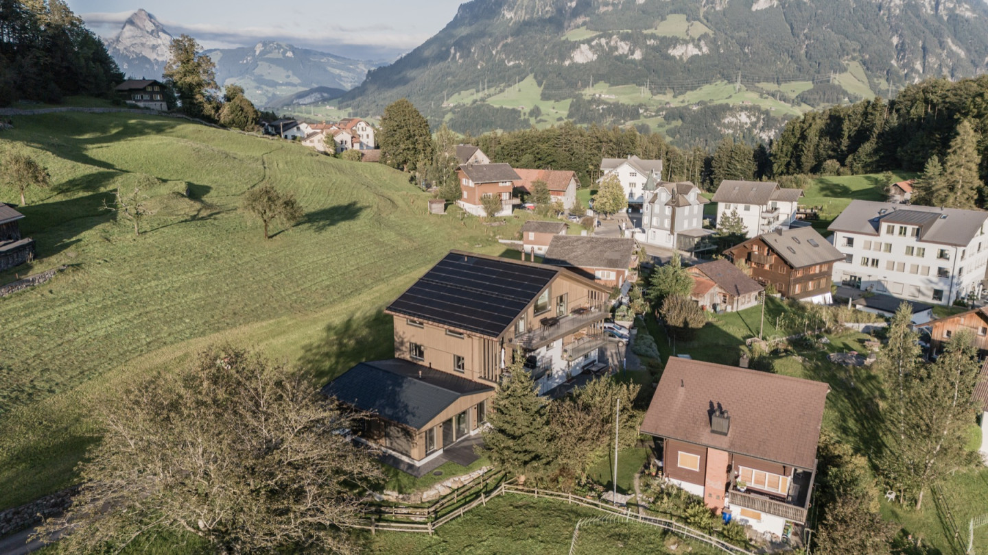 Drohnenaufnahme mit Blick über das Dorf und die umliegende Bergkette
