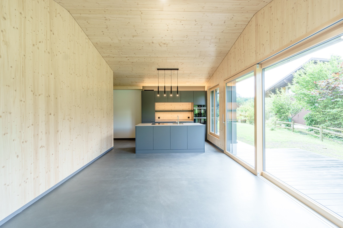 Offene Küche mit Kochinsel und grosser Fensterfront zum Garten